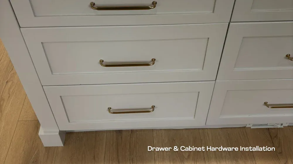 Close-up of modern brass pull hardware installed on shaker-style kitchen drawers.