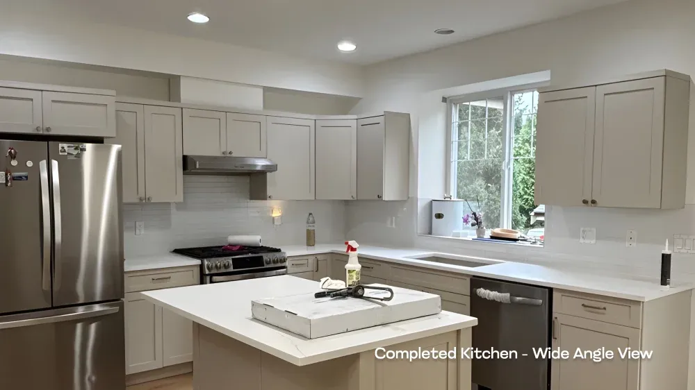 Wide-angle view of a completed modern kitchen renovation in Langley, BC, featuring a central island and seamless finishes.