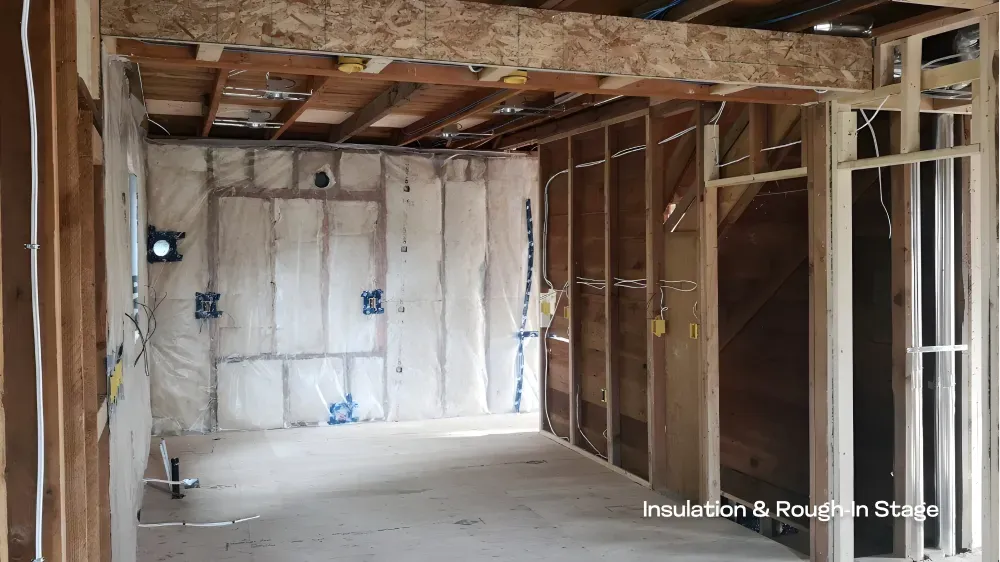 renovation-rough-in.webp	A residential space during the insulation and structural framing rough-in stage of construction, a PCC Vancouver project. — before