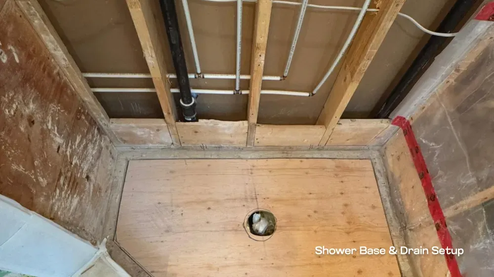 The structural framing and drain setup for a custom shower base during a residential bathroom renovation by PCC Vancouver. — before