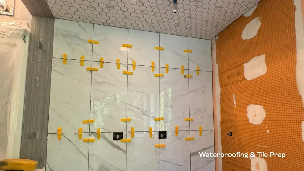 Waterproofing membranes and marble-style wall tile installation in progress for a high-end bathroom remodel by PCC.